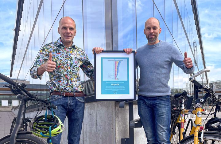 Rickard Malmström (MP) och Daniel Fritz med årets diplom från Cykelfrämjandet framför Uppsalas cykelparkeringshus.
