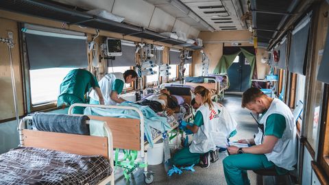 Personal på intensivvårdsavdelningen på Läkare Utan Gränsers tåg övervakar och stabiliserar en svårt krigsskadad patient under en resa från Pokvrosk i östra Ukraina till Lviv i västra Ukraina. Resan tar ungefär 20 timmar. Foto: Andrii Ovod.