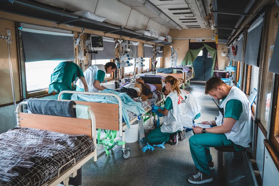 Personal på intensivvårdsavdelningen på Läkare Utan Gränsers tåg övervakar och stabiliserar en svårt krigsskadad patient under en resa från Pokvrosk i östra Ukraina till Lviv i västra Ukraina. Resan tar ungefär 20 timmar. Foto: Andrii Ovod.