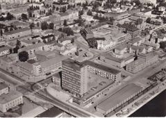 Umeå centrum från ovan, 1965. Renmarkstorget är vid den här tidpunkten inget torg, utan en esplanad anpassad för fordonstrafik. Sträckningen av esplanaden följer Renmarksbäcken, som i slutet av 1800-talet kulverterades för att ge plats för esplanaden. Torgets annorlunda form beror alltså ursprungligen på Renmarksbäcken. Foto: Lantmäteriets fotoarkiv