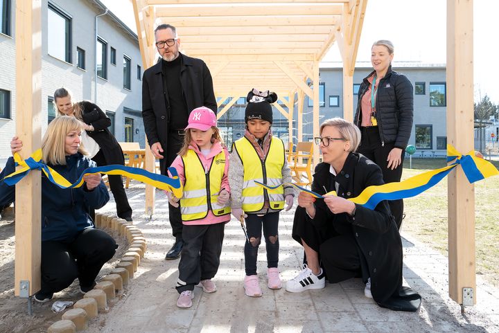 Bandklippning med rektor Maria Carlsson, förskolebarnen Alva och Noelle samt Jennie Claesson, ordförande i utbildningsnämnden. I bakgrunden: Skolfastigheters fastighetschef Peter Walhed och Therése Berglind, fastighetsförvaltare.