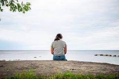 Ensam flicka sitter på klippa vid havet och tittar ut. Foto: Per Boge/Mostphotos