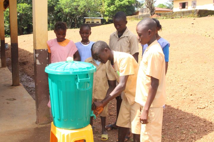 Barn i Guinea tvättar händer på en skolgård. Foto: Plan International.