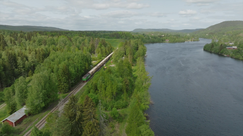 Green Cargos godståg passerar genom Borlänges landskap.