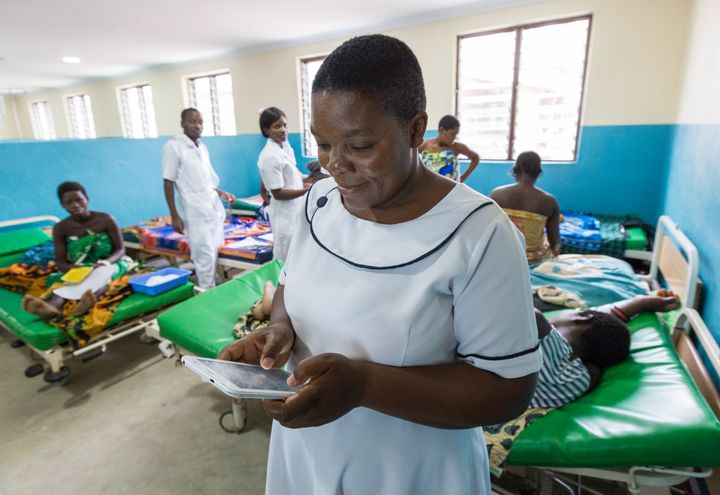 På Malawi har mobildata använts för att förstå var hälsokliniker gör mest nytta. Foto: Christopher Neu, TechChange/Dial
Syntolkning: Kvinnlig vårdpersonal använder en pekskärm i en sal med patienter.