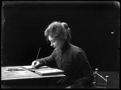 Fotograf Märta Kristina Rådström retuscherar med pensel ett visitkortsporträtt. Fotograf: Gustaf Klemming, 1903.