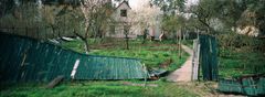 Ett förstört staket ger en tillfällig utsikt över trädgården till ett privat hus i Irpin. Bilden tagen 2022-04-25. Foto: Sergii Polezhaka