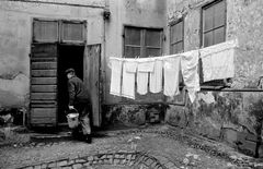 Norra Smedjegatan. Kullerstensbelagd gård med hängande tvätt och en man med en hink. Foto: Manne Lind