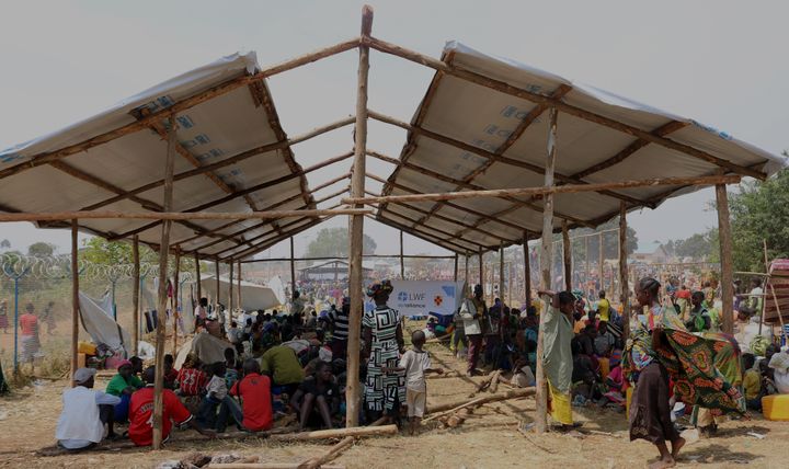 Nyanlända flyktingar väntar vid Kagoma mottagningsstation under temporära skydd för solen, uppförda av Lutherska Världsförbundets Uganda-kontor med stöd av Svenska kyrkans internationella arbete. Foto: LWF Uganda.