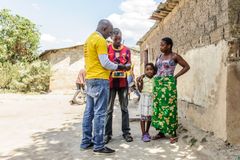 Owen Sinkala från ReadyPay i Zambia kontrollerar familjens solelssystem. På sina kundresor i byarna kontrollerar han också att allt fungerar bra med företagets representant i byn och att invånarna är nöjda.
