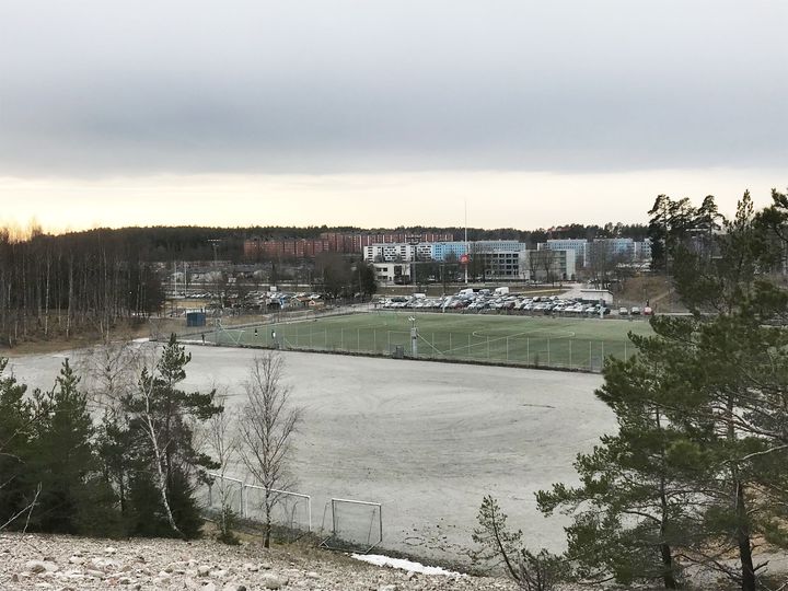 Området där den nya fotbollshallen ska placeras. Bortom fotbollsplanen skymtar Väsby centrum. Cirka 100 meter söder om grusplanen (till vänster i bilden) ligger friidrottsplatsen.