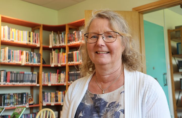 Katarina Strömberg framför bokhyllor i ett bibliotek