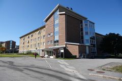 Fyravåningshus i tegel med stora fönster och en gångväg framför.