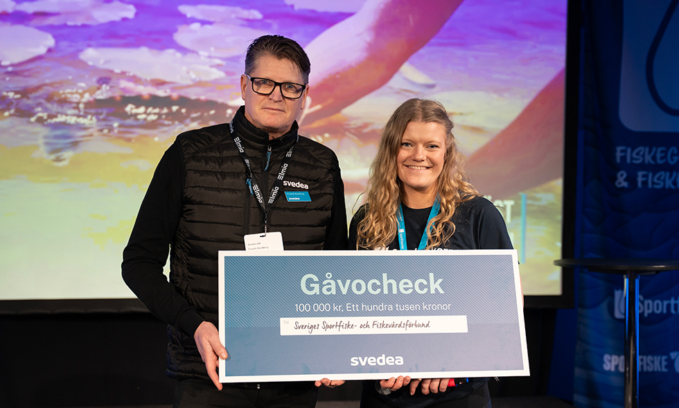 Fredrik Nordberg, chef partnersälj fritid på Svedea, överräcker checken till Hanna Eriksson, nationellt ungdomsansvarig, Sportfiskarna.