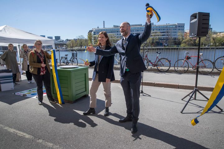 Trafikdirektör Gunilla Glantz och trafikborgarråd Lars Strömgren inviger årets sommarplatser på Bergsunds strand genom att klippa ett blå-gult invigningsband.