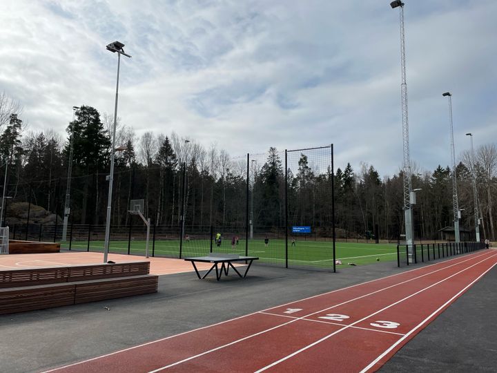 En fotbollsplan med konstgräs med tre löparbanor i förgrunden.