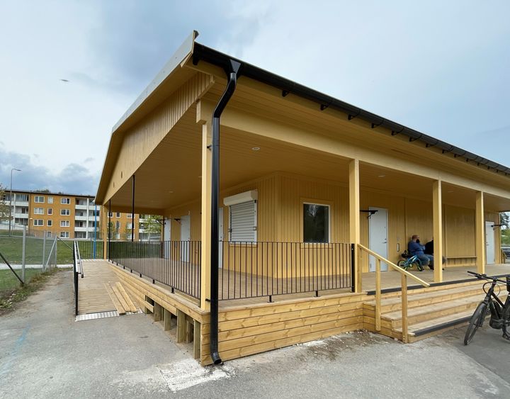 En gul träbyggnad med altan under tak.