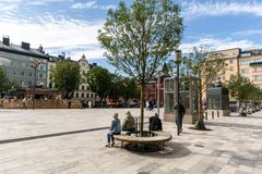 Träd planterat innanför rund sittbänk på torget.