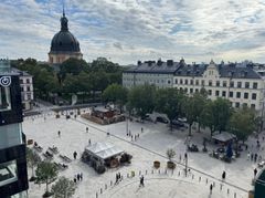 Torg med människor, sett snett ovanifrån, kyrka i bakgrunden.