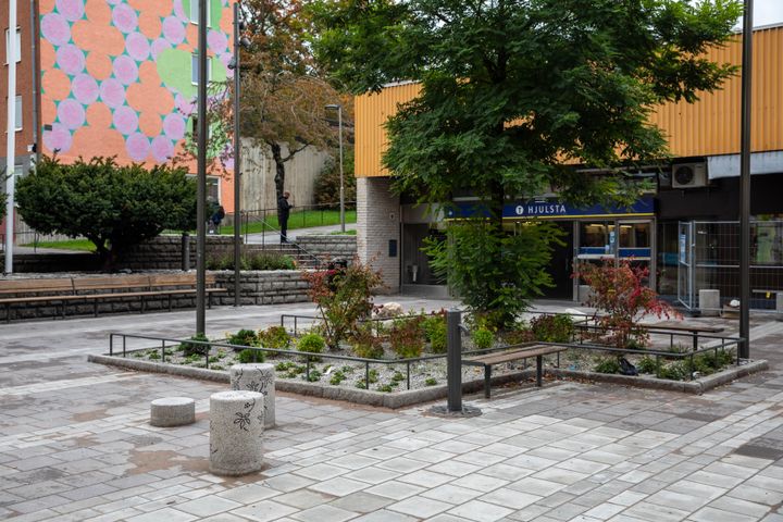 Planteringar, trafikhinder och träd på ett torg. Ingång till tunnelbanan syns i bakgrunden.