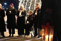 Människor på rad framför julbelysning.