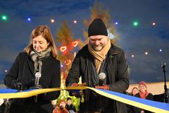 Två personer klipper ett gult och blått invigningsband med sax.