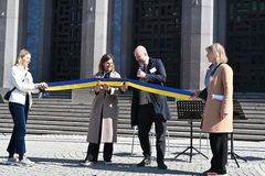Två personer klipper ett blågult band.