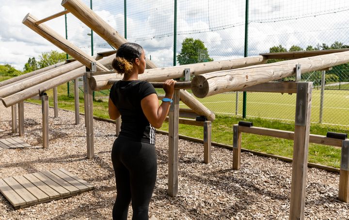 En person lyfter stockar i ett utegym.