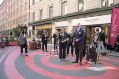 Personer på gata, gatan är målad rosarandig.