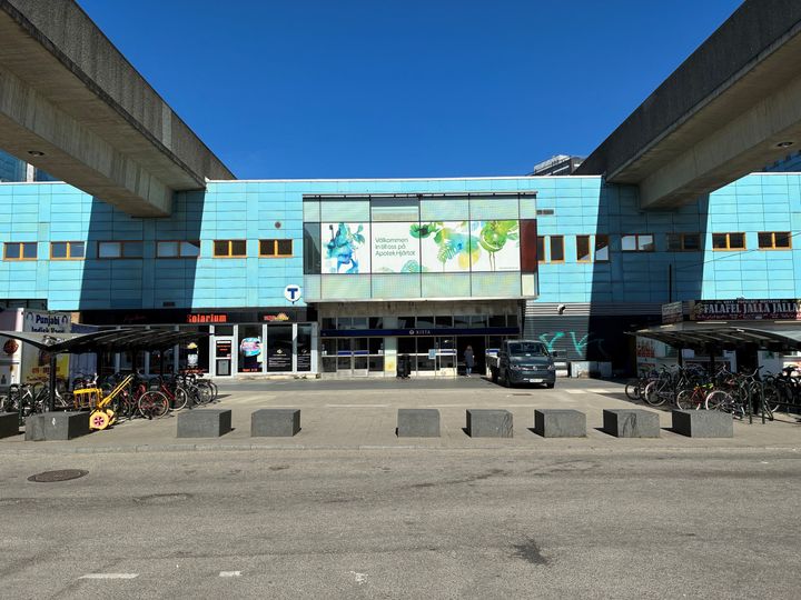 Ett torg med stenklumpar och en blå byggnad i bakgrunden