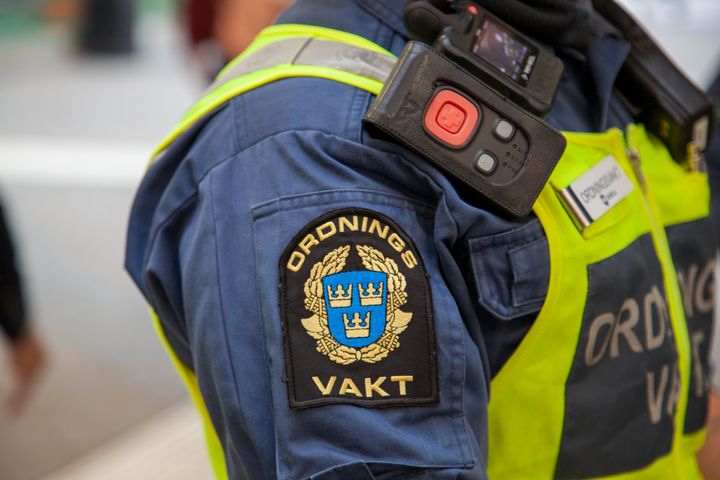 Detaljbild med emblem för ordningsvakt på en persons ärm.