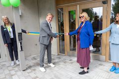 En man och en kvinna klipper ett blågult band vid en invigning utanför en byggnad. Två andra personer står bredvid.