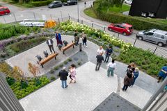 Flera personer står och pratar i en trädgård med gångvägar och bänkar.