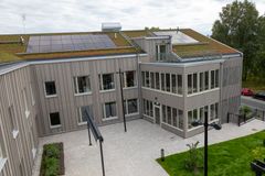 Modernt tvåvåningshus med solpaneler och grönt tak.