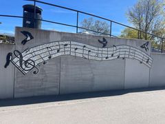 Mosaik av musiknoter på en betongvägg utomhus.
