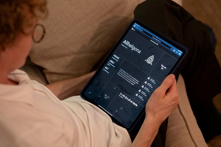 En ung man sitter i soffan med en läsplatta i handen.