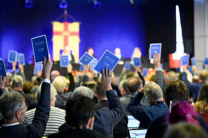 Kyrkomötets ledamöter röstar genom att hålla upp sina röstkort.