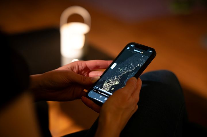 Person håller en smartphone som visar en karta i mörkt rum.