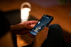 A person holding a smartphone displaying digital candles.