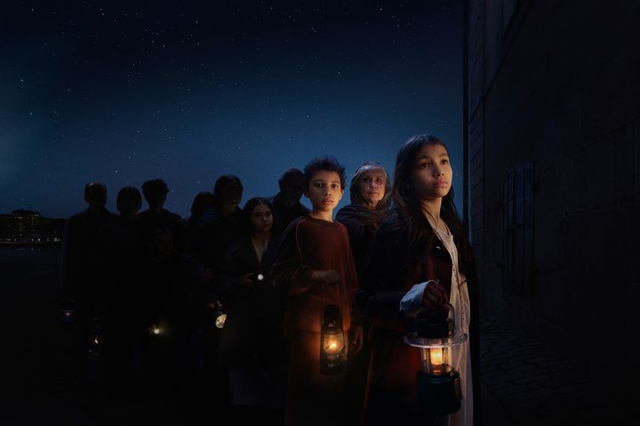 En grupp människor står utomhus på natten, alla håller i lyktor.