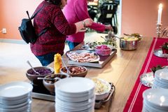 Två personer serverar sig mat från ett julbord med olika rätter.