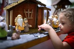 A young child interacts with a Christmas nativity scene.