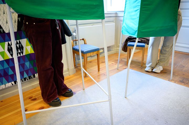 Två personer står i varsitt grönt valbås.