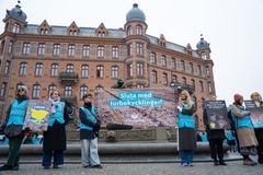 En grupp människor håller upp protestskyltar framför en stor byggnad.