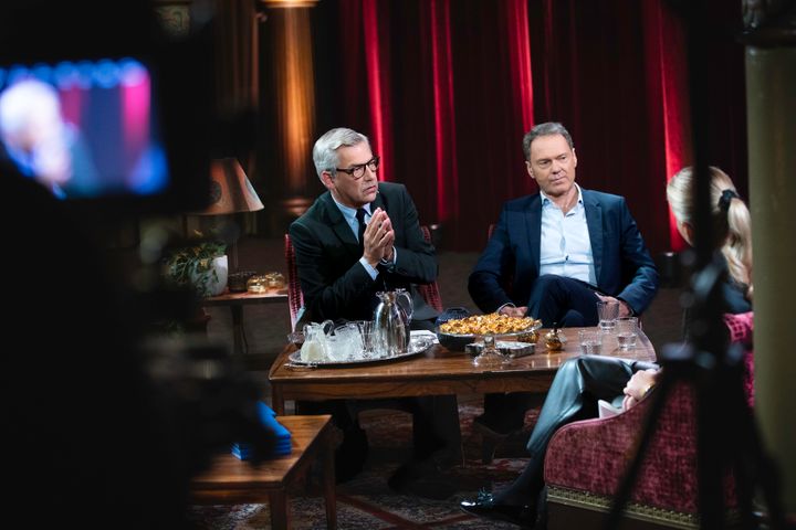 Anders Kraft och Niklas Ekdal sitter mitt i ett samtal i en TV-studio. En videokamera ur fokus i förgrunden filmar dem.