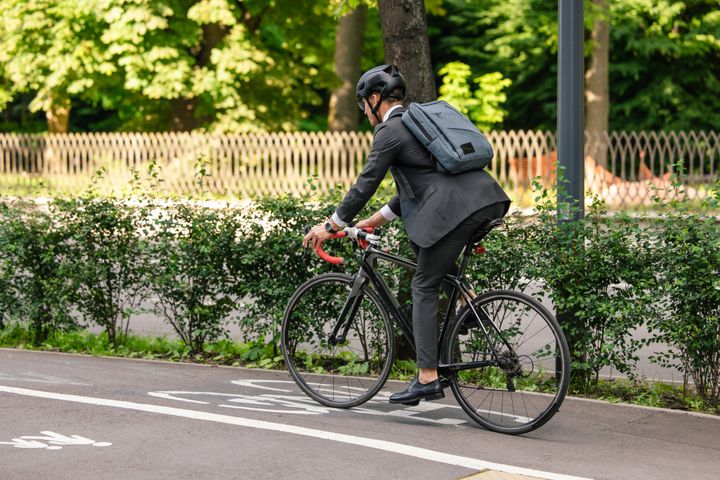 Person som cyklar i kostym med ryggsäck