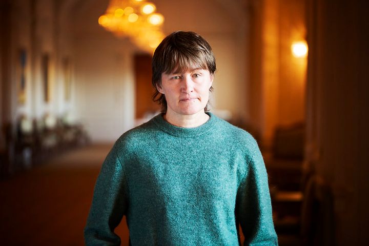 Malin Östh står i en grön tröja och tittar in i kameran