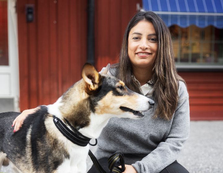 Nooshi Dadgostar sitter och ler och klappar en hund som heter Bilbo.