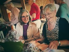 Marita Alsén har i många år hjälpt till att hålla Örtomta kyrka öppen. Här bläddrar hon och biskop Marika Markovits i broschyren.