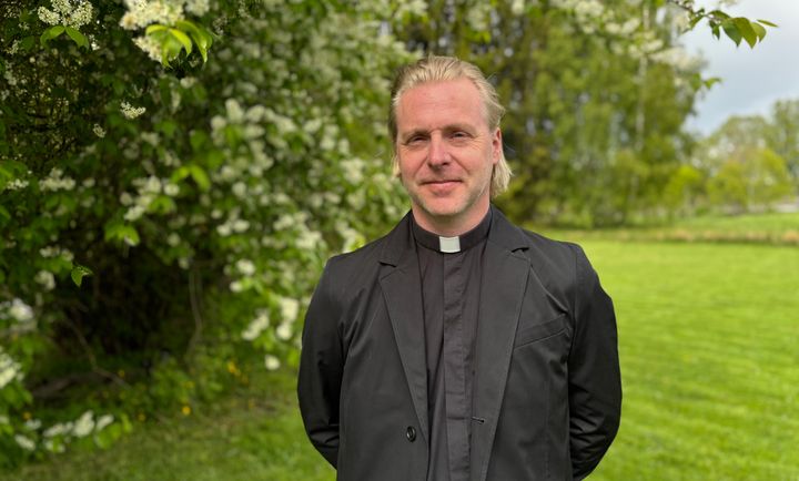 Porträttfoto på kyrkoherde Magnus Segendorff framför en grönskande buske